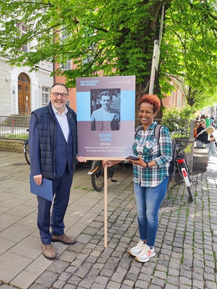 Anton Biebl und Yirgalem Fisseha Mebrahtu mit einem Schild für Georg Elser in der Türkenstraße