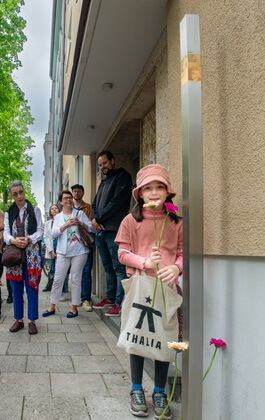 Child with flowers standing next to the Memorial Signs for Emma and Jakob Springer