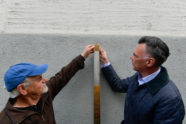 Bruce Neuburger und Stadtrat Michael Dzeba bringen das Erinnerungszeichen für Will (Wolf) Holzer an