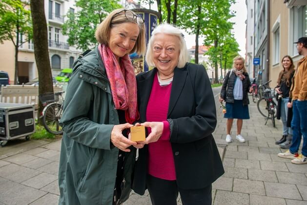 A relative and Janne Weinzierl of the District Committee Schwabing-Freimann showing one of the Memorial Signs