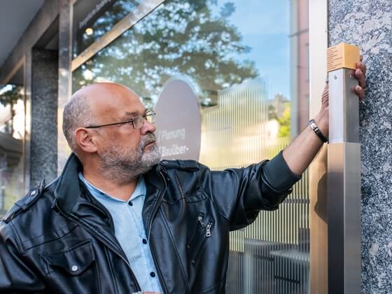 Arnold Schuster, ein Angehöriger Hedwig Schusters, bringt das Erinnerungszeichen an