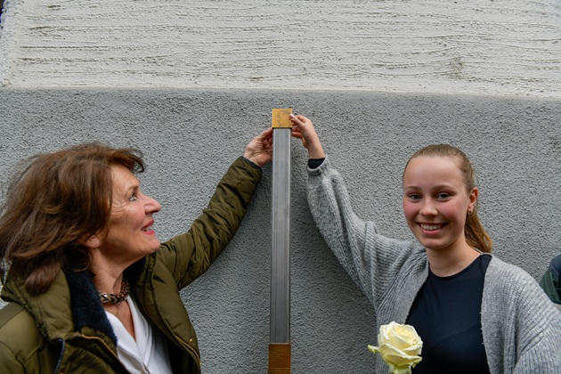 Gabriela Schneider, Liberale Jüdische Gemeinde München Beth-Shalom e.V., und eine Schülerin bringen das Erinnerungszeichen für Benno Holzer an