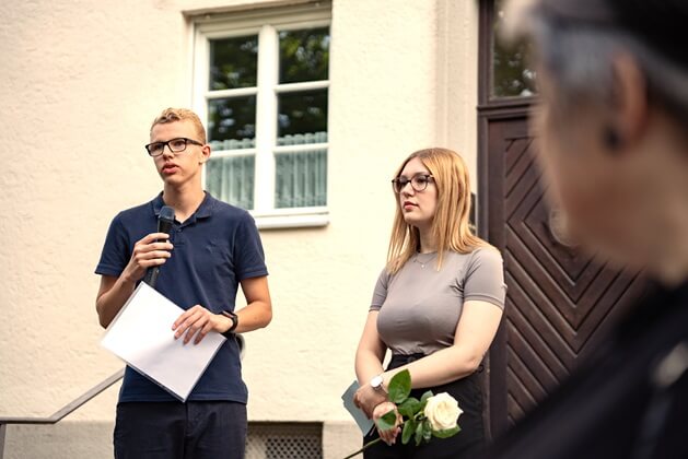 Carina Findl und Fynn Kukla, Auszubildende der Münchner Wohnen, verlesen die Biografie von Alois Koller