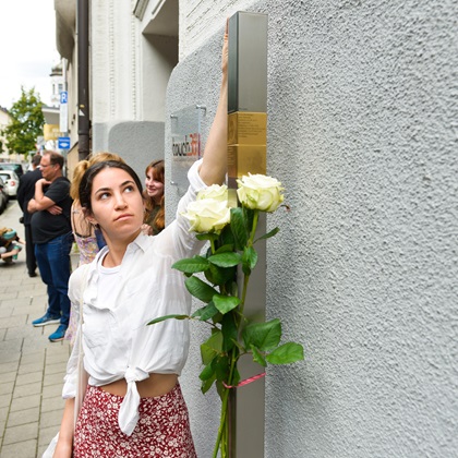 Eine junge Angehörige neben den Erinnerungszeichen für Benno und Anna Neuburger