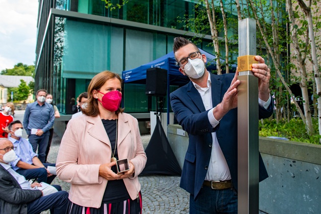 Bürgermeisterin Verena Dietl und Sascha Lickes bringen das Erinnerungszeichen an